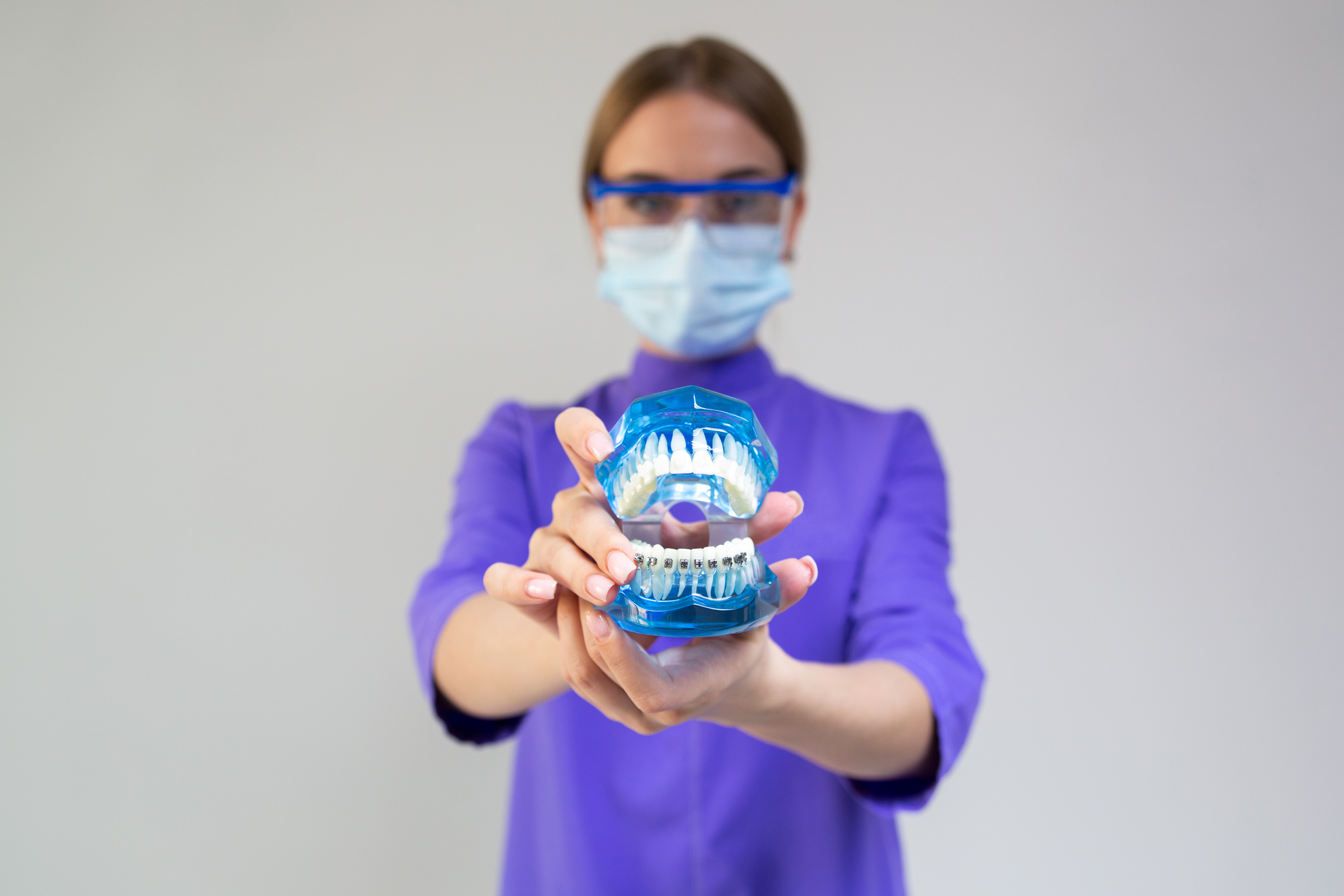 Woman dentist demonstrating plastic dental cleaning system with braces